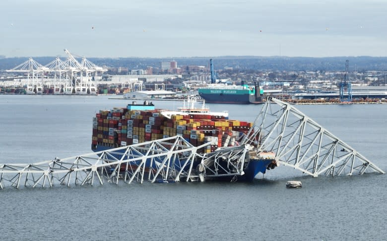 The steel frame of the Francis Scott Key Bridge sits on top of a container ship after the bridge collapsed on March 26. (Jim Watson/AFP via Getty Images)