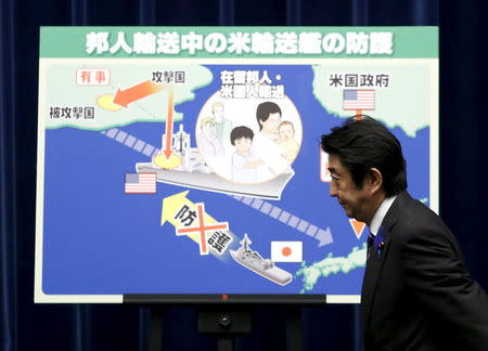 Japan's Prime Minister Shinzo Abe arrives at a news conference in front of a placard showing a defensive scenario for the protection of Japanese nationals overseas, at his official residence in Tokyo in this July 1, 2014 file photo. REUTERS/Yuya Shino/Files