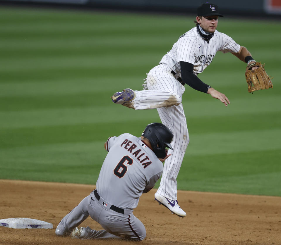 FILE - Colorado Rockies second baseman Ryan McMahon, top, jumps over Arizona Diamondbacks' David Peralta after forcing him out at second base on a double play hit into by Christian Walker in the sixth inning of a baseball game in this file photograph taken Tuesday, Aug. 11, 2020, in Denver. McMahon is slated to return to his natural position, third base, with the trade of Nolan Arenado to St. Louis in the off-season. (AP Photo/David Zalubowski, File)