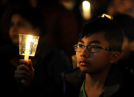 A boy holds up a candle during a vigil for Srinivas Kuchibhotla, an Indian engineer who was shot and killed, at a conference center in Olathe, Kansas, U.S., February 26, 2017. REUTERS/Dave Kaup