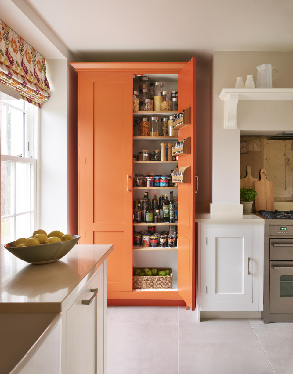 An orange larder in a well organized white kitchen scheme.