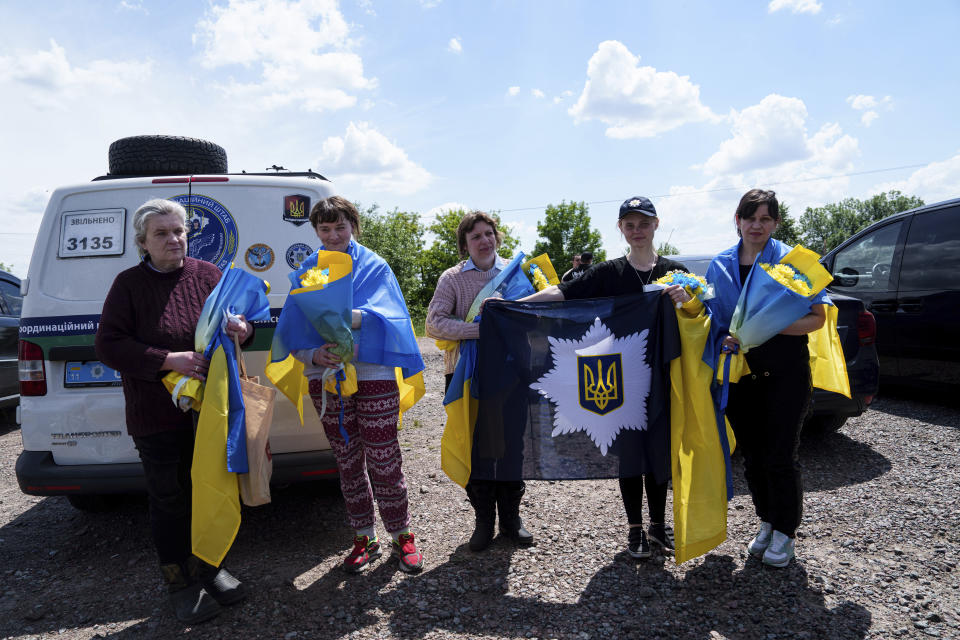 Ukrainian female servicemen and civilians pose with National flags after returning from captivity during POWs exchange in Sumy region, Ukraine, Friday, May 31, 2024. Ukraine returned 75 prisoners, including four civilians, in the latest exchange of POWs with Russia. It's the fourth prisoner swap this year, and 52nd since Russia invaded Ukraine. In all, 3 210 Ukrainian servicemen and civilians were returned since the outbreak of the war. (AP Photo/Evgeniy Maloletka)