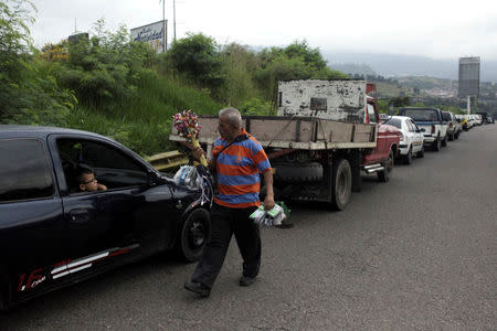 Un vendedor junto a vehículos en la fila de espera para comprar combustible cerca de una gasolinera de PDVSA en San Cristóbal, Venezuela, nov 10, 2018. REUTERS/Carlos Eduardo Ramirez