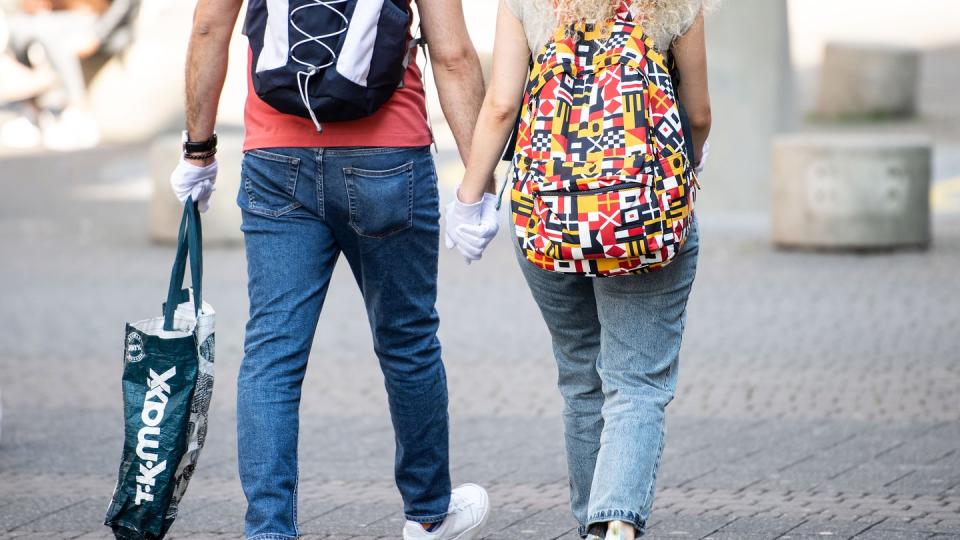 Ein Pärchen trägt während eines Einkaufsbummels auf der Schildergasse in Köln Schutzhandschuhe.