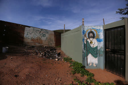 A painting of Jesus Christ is seen on the wall of a house, next to a section of the border fence separating Mexico and the United States, on the outskirts of Tijuana, Mexico. REUTERS/Edgard Garrido
