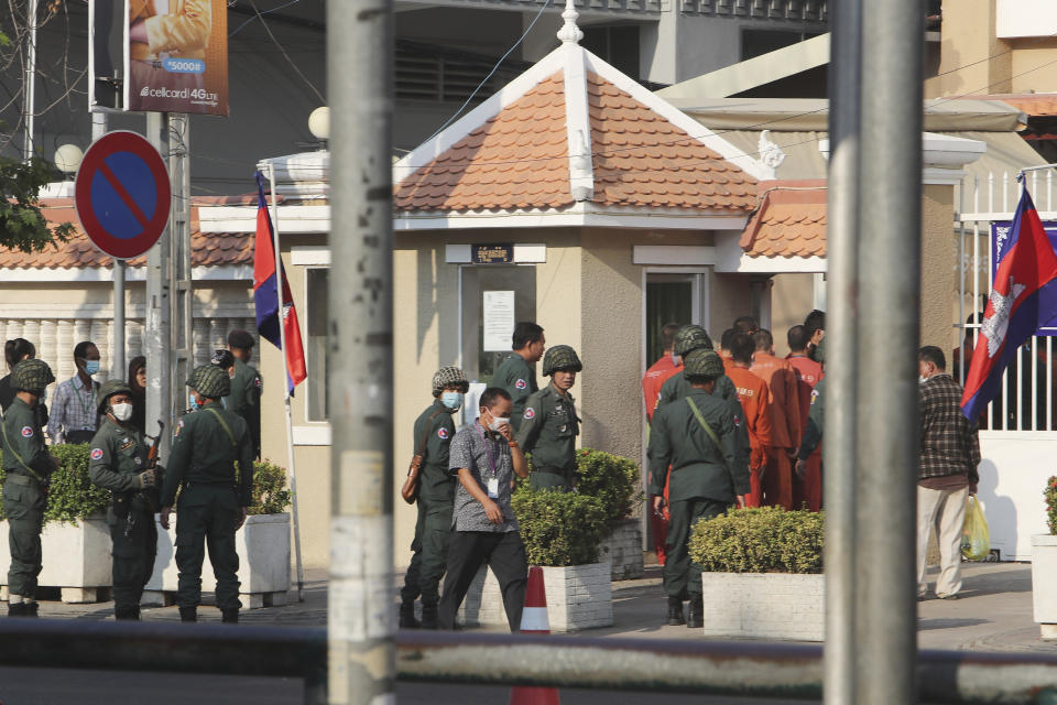 Cambodian police officers escort prisoners, in orange clothes, including Rong Chhun, president of the Cambodian Confederation of Unions, as they enter the Phnom Penh Municipal Court in Phnom Penh, Cambodia Friday, Jan. 15, 2021. The trial of the Cambodian labor union leader charged with inciting social unrest opened Friday, part of a large-scale legal offensive by the government against its critics. (AP Photo/Heng Sinith)