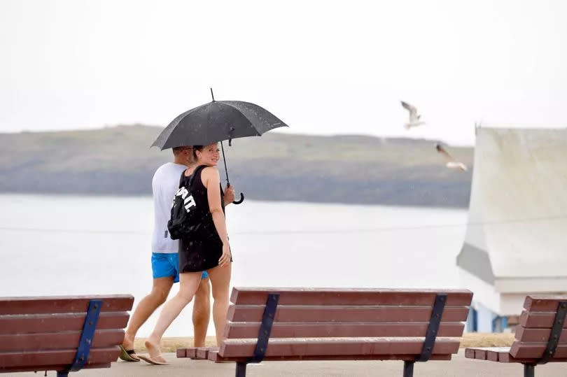 A couple walking on Barry Island with an umbrella