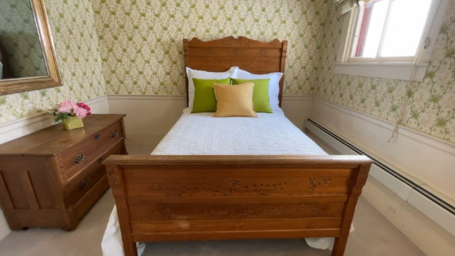 A small bedroom includes a wooden dresser and a matching bedframe.