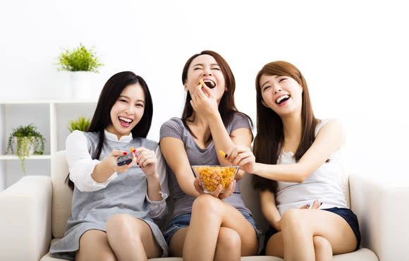 Three young women watch TV.