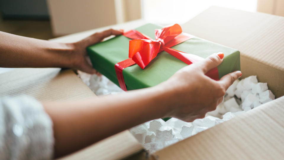 A person unwrapping a Christmas gift that was mailed to them