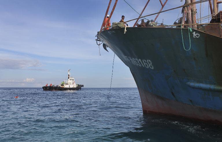 Photo released on April 19, 2013 shows the Chinese fishing boat (R) that ran aground off Tubbataha Reef being towed away by a tugboat