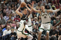 Miami Heat forward Duncan Robinson, top left, looks for an opening through the defense of Boston Celtics center Kristaps Porzingis (8), guard Jrue Holiday (4), and guard Payton Pritchard (11) during the first half of an NBA basketball game, Sunday, Feb. 11, 2024, in Miami. (AP Photo/Rebecca Blackwell)