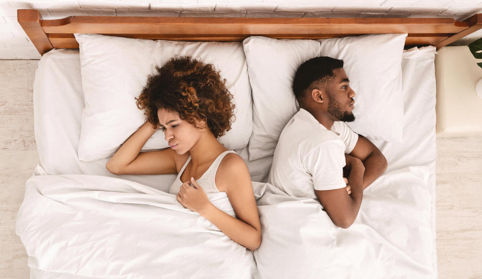 Upset young black couple having marital problems or disagreement. lying back to back, ignoring each other in bed, top view