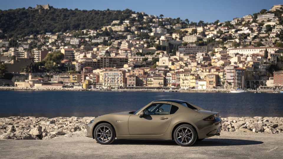 mazda miata parked in front of river and cityscape