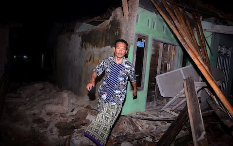 A man is seen near a damaged house after an earthquake recorded at 7.3 magnitude on the Richter scale in Sumelap village, Tasikmalaya, West Java, Indonesia  - Credit: Moch Bustomi/Anadolu Agency