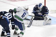 Winnipeg Jets goaltender Laurent Brossoit (30) makes a save on Vancouver Canucks' Brock Boeser (6) during the third period of an NHL game in Winnipeg, Manitoba, Monday, May 10, 2021. (Fred Greenslade/The Canadian Press via AP)