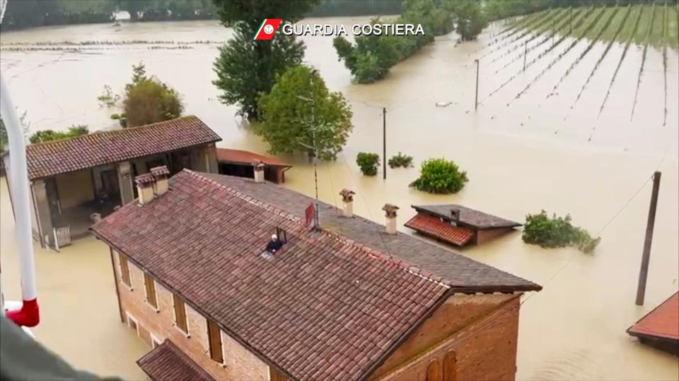 This photo provided by the Italian Coast guard shows a man on the roof of a flooded house just before being rescued by helicopter, in the area of the town of Faenza in the northern Italian region of Emilia Romagna, Wednesday, May 17, 2023.