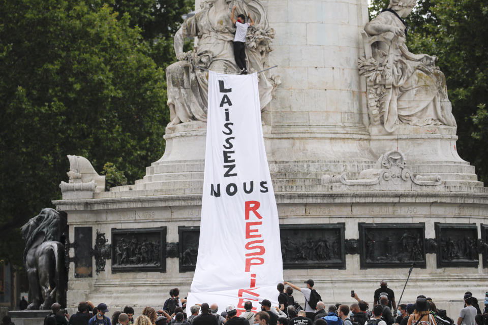 People hang a banner thet reads "Let us breathe" on a statue during a protest in memory of Lamine Dieng, a 25-year-old Franco-Senegalese who died in a police van after being arrested in 2007, in Paris, Saturday, June 20, 2020. Multiple protests are taking place in France on Saturday against police brutality and racial injustice, amid weeks of global anger unleashed by George Floyd's death in the US. (AP Photo/Christophe Ena)