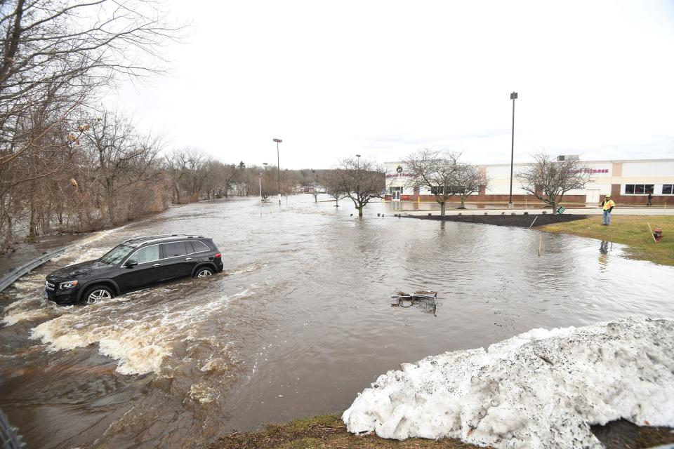 A car is partly submerged in the Norwichtown Commons parking lot as the Yantic River floods Wednesday. All the businesses there were closed.