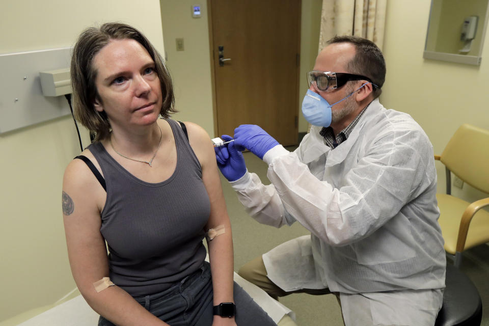 FILE - In this March 16, 2020 file photo, a pharmacist gives Jennifer Haller, left, the first shot in the first-stage safety study clinical trial of a potential vaccine for COVID-19, the disease caused by the new coronavirus, at the Kaiser Permanente Washington Health Research Institute in Seattle. The world's biggest COVID-19 vaccine test got underway Monday, July 27 with the first of 30,000 planned volunteers. The experimental vaccine is made by the National Institutes of Health and Moderna Inc., and it's one of several candidates in the final stretch of the global vaccine race. (AP Photo/Ted S. Warren, File)