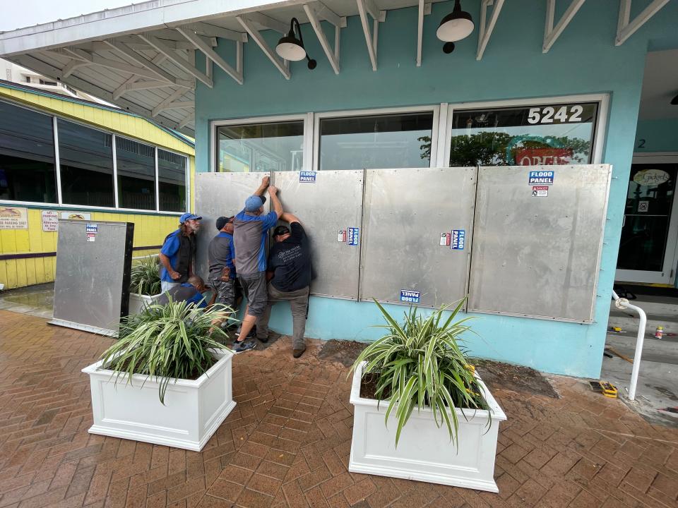 Workers for Daiquiri Deck work to board up a business on Ocean Boulevard on Siesta Key board up part of the store in advance of mandatory evacuations of the barrier island and closing Tuesday.