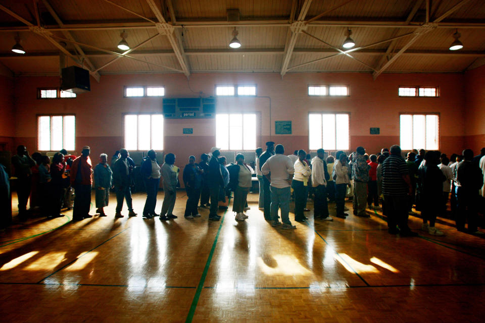 African-Americans line up to vote in a gym.