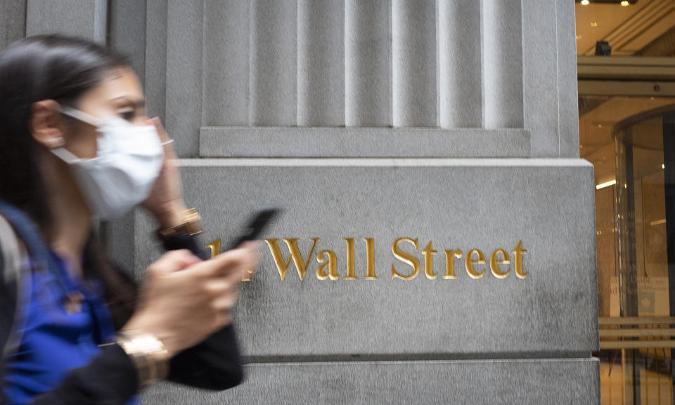 A woman wearing a mask passes a sign for Wall Street, Tuesday, June 30, 2020, during the coronavirus pandemic. (AP Photo/Mark Lennihan)