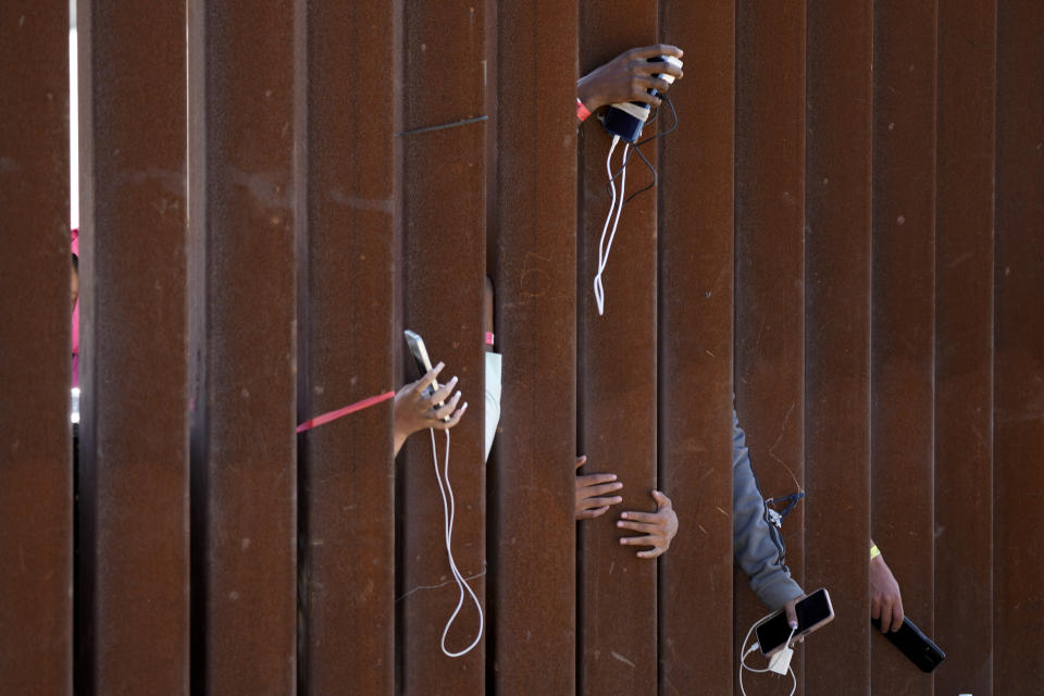 Migrants waiting to apply for asylum between two border walls hold out phones in hopes of getting a charge on May 11, 2023, in San Diego. Pandemic-related U.S. asylum restrictions, known as Title 42, expired on May 11. (AP Photo/Gregory Bull)