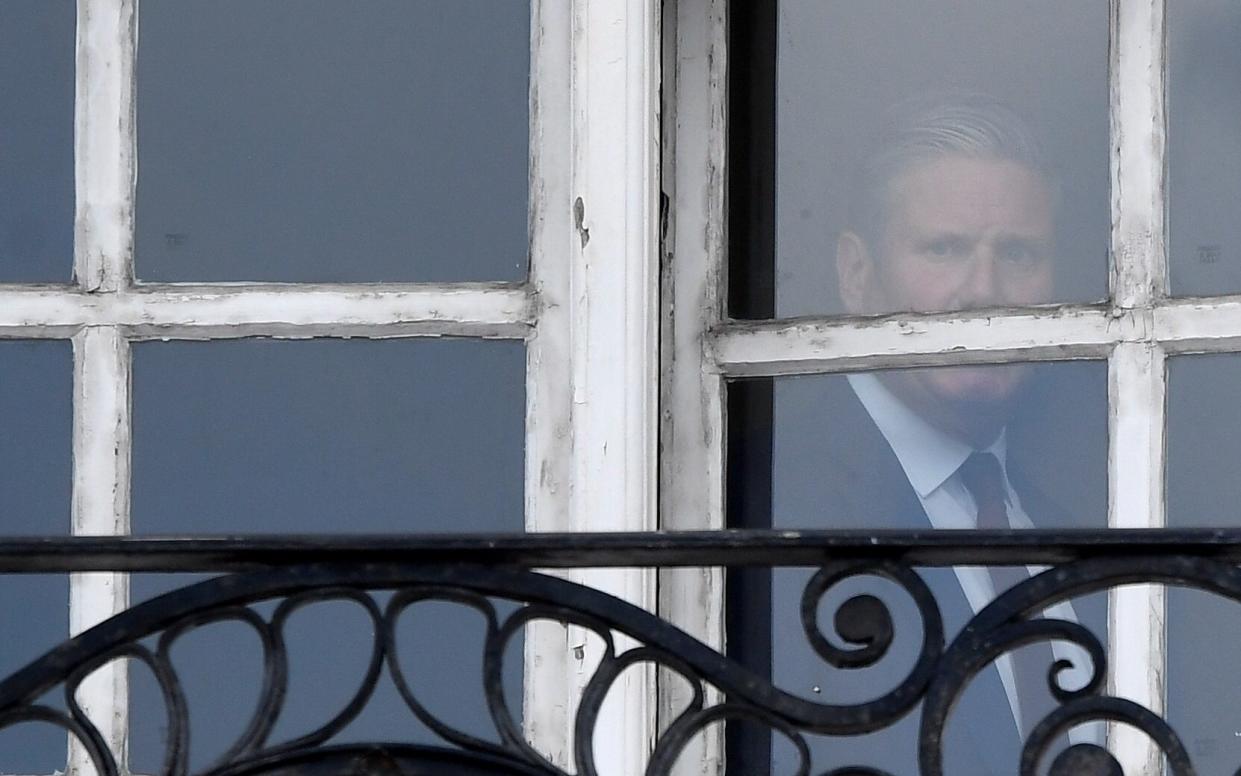 Keir Starmer is seen in the window of his offices in London - TOBY MELVILLE/REUTERS