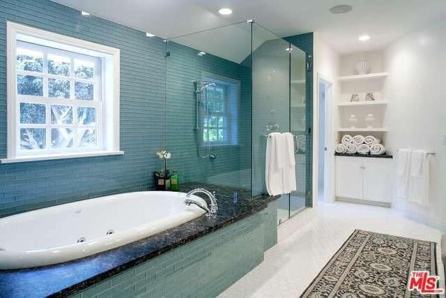 <p>The master bathroom has a glass-door shower and soaker tub. There are four bathrooms in total. (Realtor.com) </p>