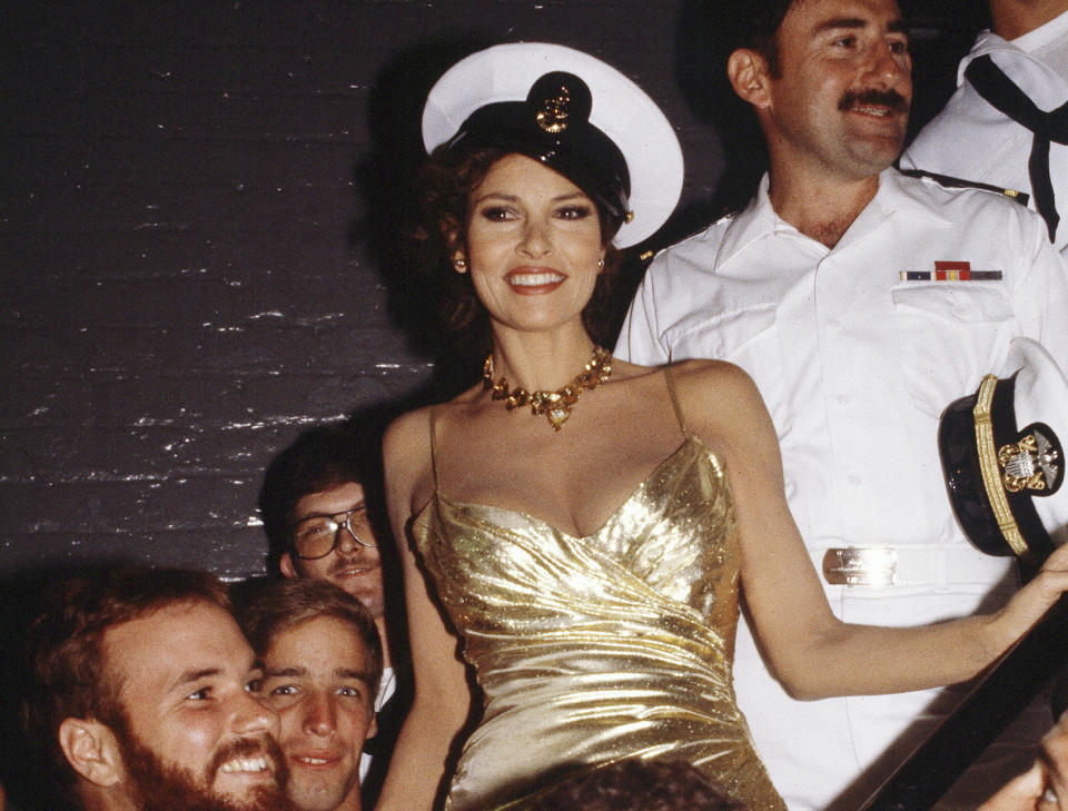 FILE - Actress Raquel Welch, starring in Broadway Musical "Woman of the Year," poses with sailors from the aircraft carrier USS Saipan and a few Marines on July 3, 1982 in New York. Welch, whose emergence from the sea in a skimpy, furry bikini in the film “One Million Years B.C.” would propel her to international sex symbol status throughout the 1960s and '70s, died early Wednesday, Feb. 15, 2023, after a brief illness. She was 82. (AP Photo/David Handschuh, File)