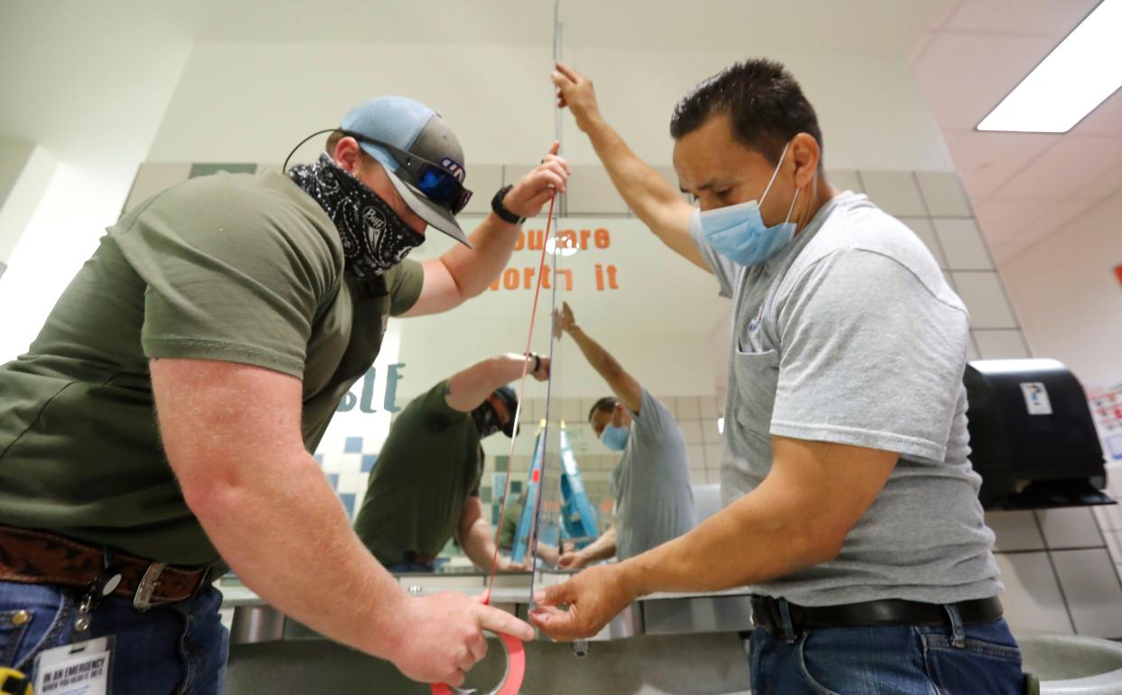 Wearing masks amid the concern of COVID-19, Richardson Independent School District workers Rogelio Ponciano, right, and Matt Attaway install a plexiglass barrier on the sink in the restroom for students at Bukhair Elementary School in Dallas, Tex. on Wednesday, July 15, 2020.