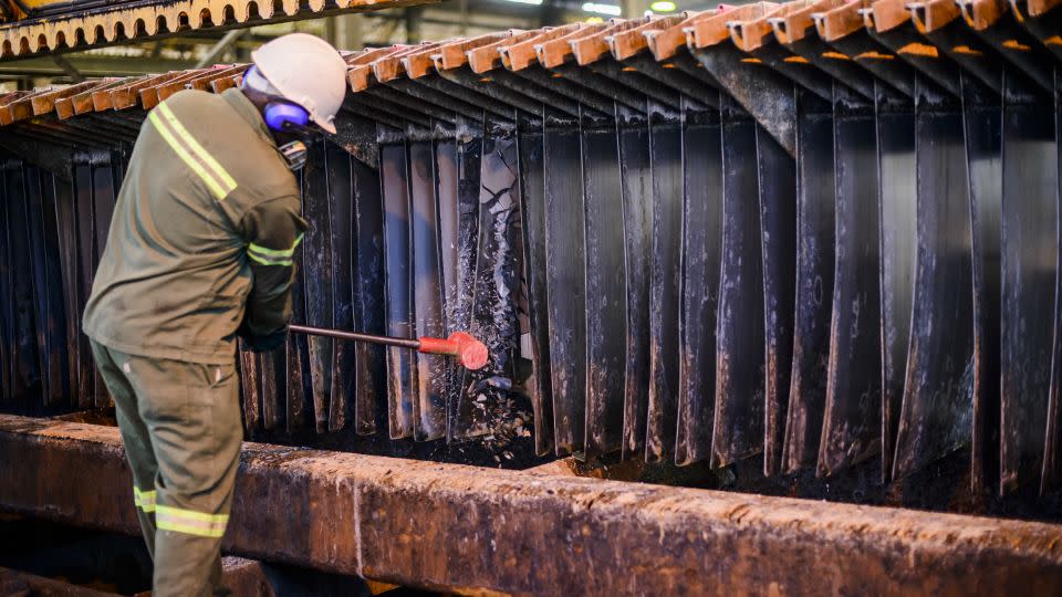 Employees at the Manganese Metal Company use rubber mallets to strip manganese away from steel sheets. The product is then washed and dried before being loaded into bags for export. - Manganese Metal Co