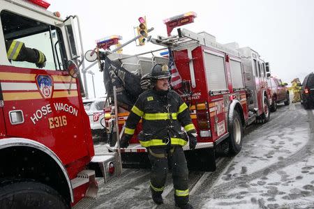 A fireman walks past firetrucks at LaGuardia Airport in New York March 5, 2015. REUTERS/Shannon Stapleton