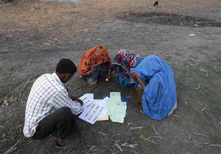 Women get their voter slips from a polling agent as they arrive to cast their vote outside a polling station in Shabazpur Dor village, in Amroha district in the northern Indian state of Uttar Pradesh April 17, 2014. REUTERS/Adnan Abidi