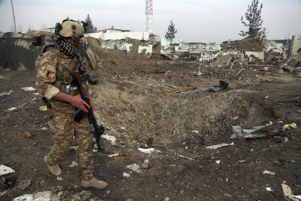 FILE - In this Nov. 29, 2018, file photo a Afghan Security forces member walks next to a crater caused by suicide bomb attack in Kabul, Afghanistan. As the Trump administration pushes for peace in Afghanistan, a new U.S. watchdog report says Afghan security forces are shrinking, gaps in security are growing, and the Taliban are largely holding their own despite a surge in American bombing. (AP Photo/Rahmat Gul, File)