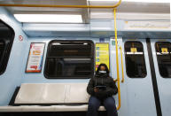 A woman wearing a face mask checks her phone in a subway in Milan, Italy, Tuesday, Feb. 25, 2020. Civil protection officials on Tuesday reported a large jump of cases in Italy, from 222 to 283. Seven people have died, all of them elderly people suffering other pathologies. (AP Photo/Antonio Calanni)