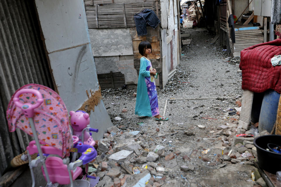 In this Tuesday. Oct. 15, 2019, photo, a girl walks on an alley in a slum in Jakarta, Indonesia. Known for his down-to-earth style with a reputation for clean governance, Indonesian President Joko Widodo's signature policy has been improving Indonesia's inadequate infrastructure and reducing poverty, which afflicts close to a tenth of Indonesia's nearly 270 million people. But raising money would be harder at a time of global economic slowdown, major trade conflicts and falling exports. (AP Photo/Tatan Syuflana)