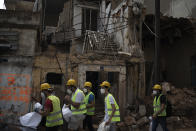 Volunteers from the American University of Beirut walk next to destroyed buildings on a neighborhood near the site of last week's explosion that hit the seaport of Beirut, Lebanon, Thursday, Aug. 13, 2020. (AP Photo/Felipe Dana)