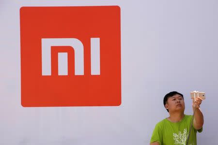 A man takes a selfie in front of the logo of Xiaomi at a venue for the launch ceremony of Xiaomi's new smart phone Mi Max in Beijing, May 10, 2016. REUTERS/Kim Kyung-Hoon