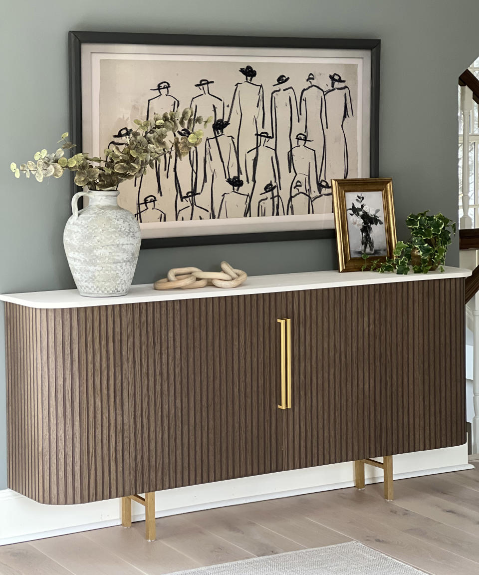 A sideboard designed with detailed fluting, gold handles and legs.