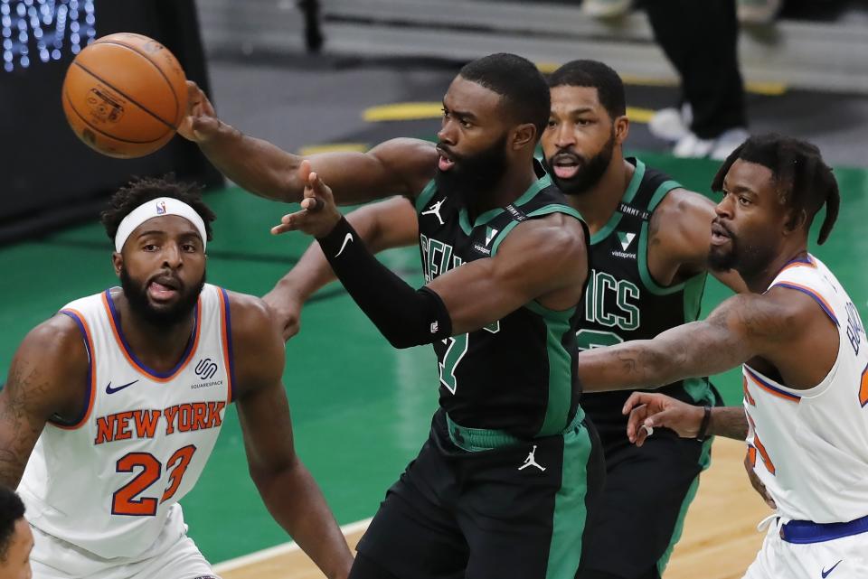 Boston Celtics' Jaylen Brown (7) passes off against New York Knicks' Mitchell Robinson (23) and Reggie Bullock, right, during the first half of an NBA basketball game, Sunday, Jan. 17, 2021, in Boston. (AP Photo/Michael Dwyer)