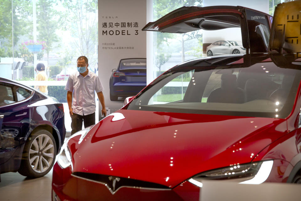 A customer wearing a face mask to protect against the new coronavirus looks at automobiles in a Tesla car showroom in Beijing, Thursday, June 11, 2020. China’s auto sales surged 14.5% in May, a second straight month of growth as the global industry’s biggest market gradually recovers from the coronavirus pandemic, the China Association of Automobile Manufacturers said Thursday. (AP Photo/Mark Schiefelbein)