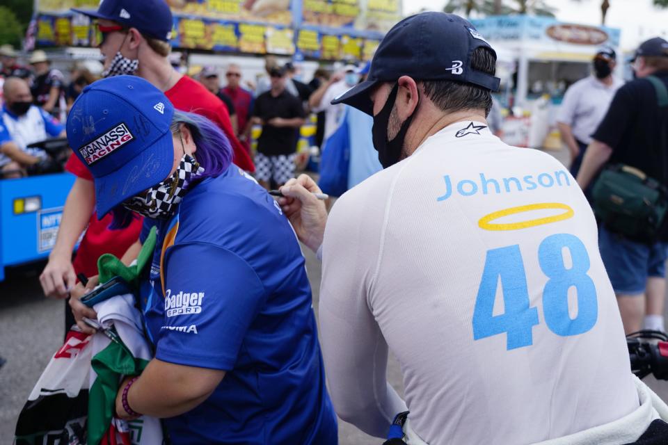 IndyCar driver Jimmie Johnson (48) signs the shirt of fan Caroline Gast of Sarasota after the morning practice session at the Grand Prix of St. Petersburg auto race, Sunday, April 25, 2021 in St. Petersburg, Fla. (Luis Santana/Tampa Bay Times via AP)