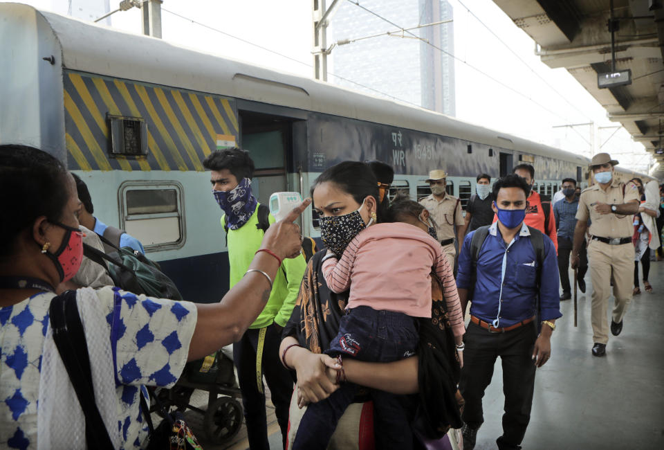 A health worker checks the temperature of a commuter at a train station in Mumbai, India, Thursday, Feb. 11, 2021. When the coronavirus pandemic took hold in India, there were fears it would sink the fragile health system of the world’s second-most populous country. Infections climbed dramatically for months and at one point India looked like it might overtake the United States as the country with the highest case toll. But infections began to plummet in September, and experts aren’t sure why. (AP Photo/Rajanish Kakade)