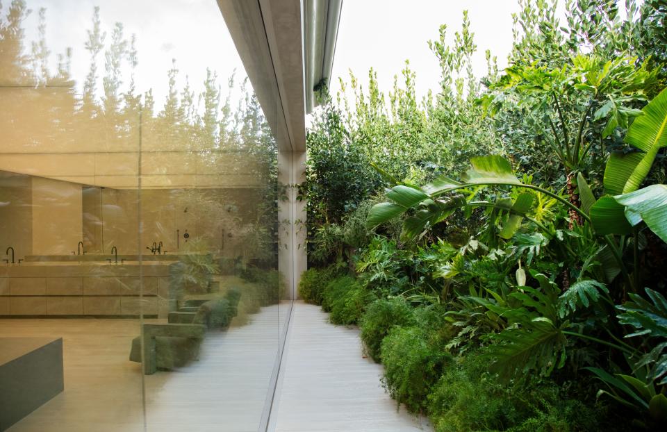 A lush garden by Wirtz International Landscape Architects shields the window-walled master bath.