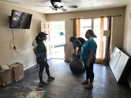 Patty Salazar (L), a volunteer from the Perales' family church, helps Luis Perales (C) and his sister Jessica Perales clean out the family home from the flooding damage caused by Hurricane Harvey, in Houston, Texas, U.S., September 1, 2017. REUTERS/Mica Rosenberg