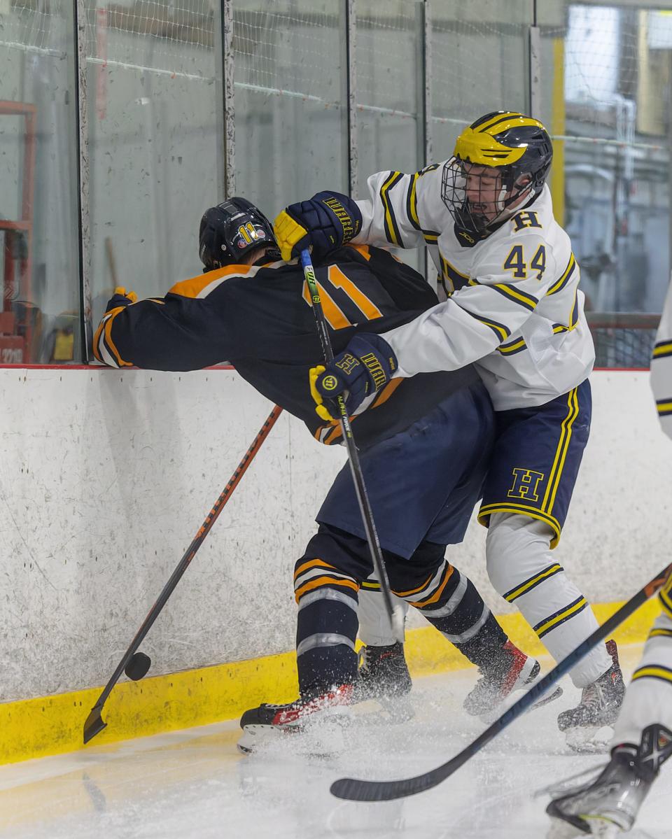 Hartland's Eli Sturos (44) battles Clarkston's Theo Walker (11) along the boards during the Eagles' 6-1 victory in a regional championship game Wednesday, March 1, 2023.