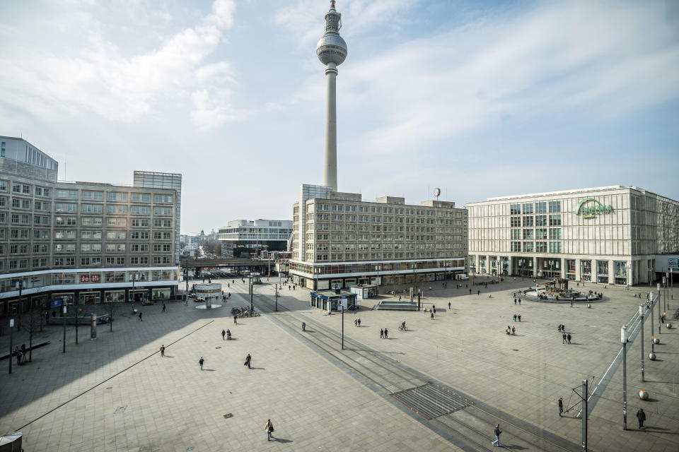 People walk across the Alexanderplatz a shopping area in Berlin, Germany, Tuesday, March 17, 2020. For most people, the new coronavirus causes only mild or moderate symptoms, such as fever and cough. For some, especially older adults and people with existing health problems, it can cause more severe illness, including pneumonia. (Michael Kappeler/dpa via AP)