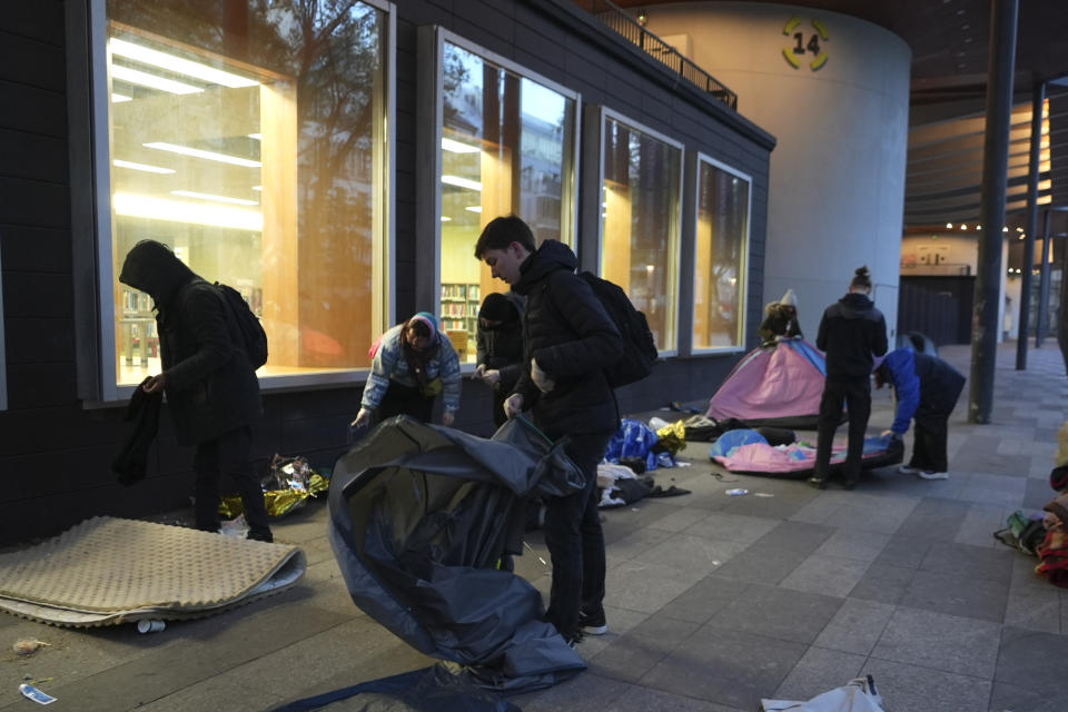 Activists help migrants to pack their belongings in a makeshift camp, early Tuesday, April 23, 2024 in Paris. French police officers have evicted migrants from a makeshift camp in Paris a few steps away from the Seine River, as similar operations have been carried out by authorities ahead of the Olympics. (AP Photo/Nicolas Garriga)